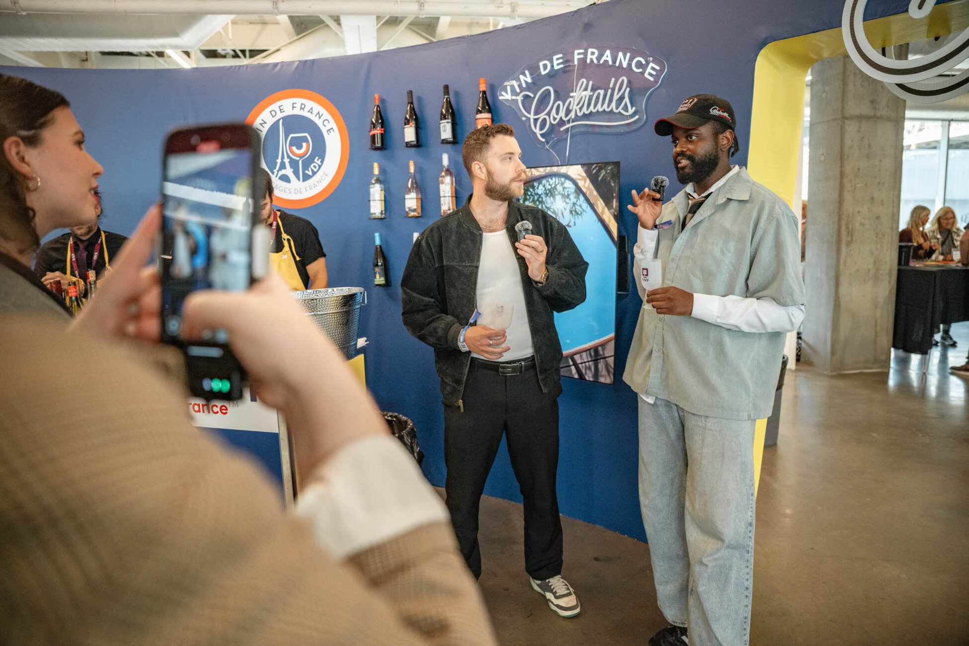 two speakers exchanging words in front of french wines display