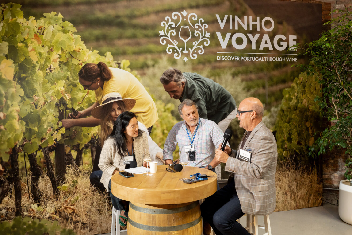 Three experts talking around a table in front of a backdrop depicting a portuguese wineyard