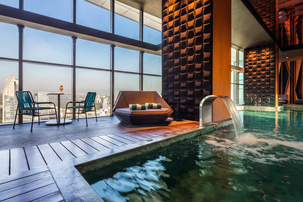 Indoor pool with modern lounge seating and panoramic city views through large windows