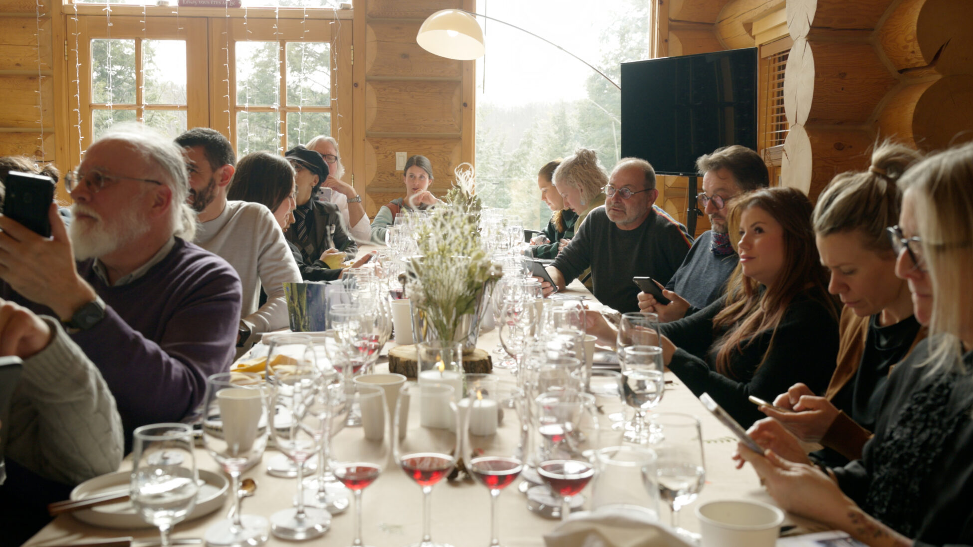 Long table of dinner filled with people and wine glasses