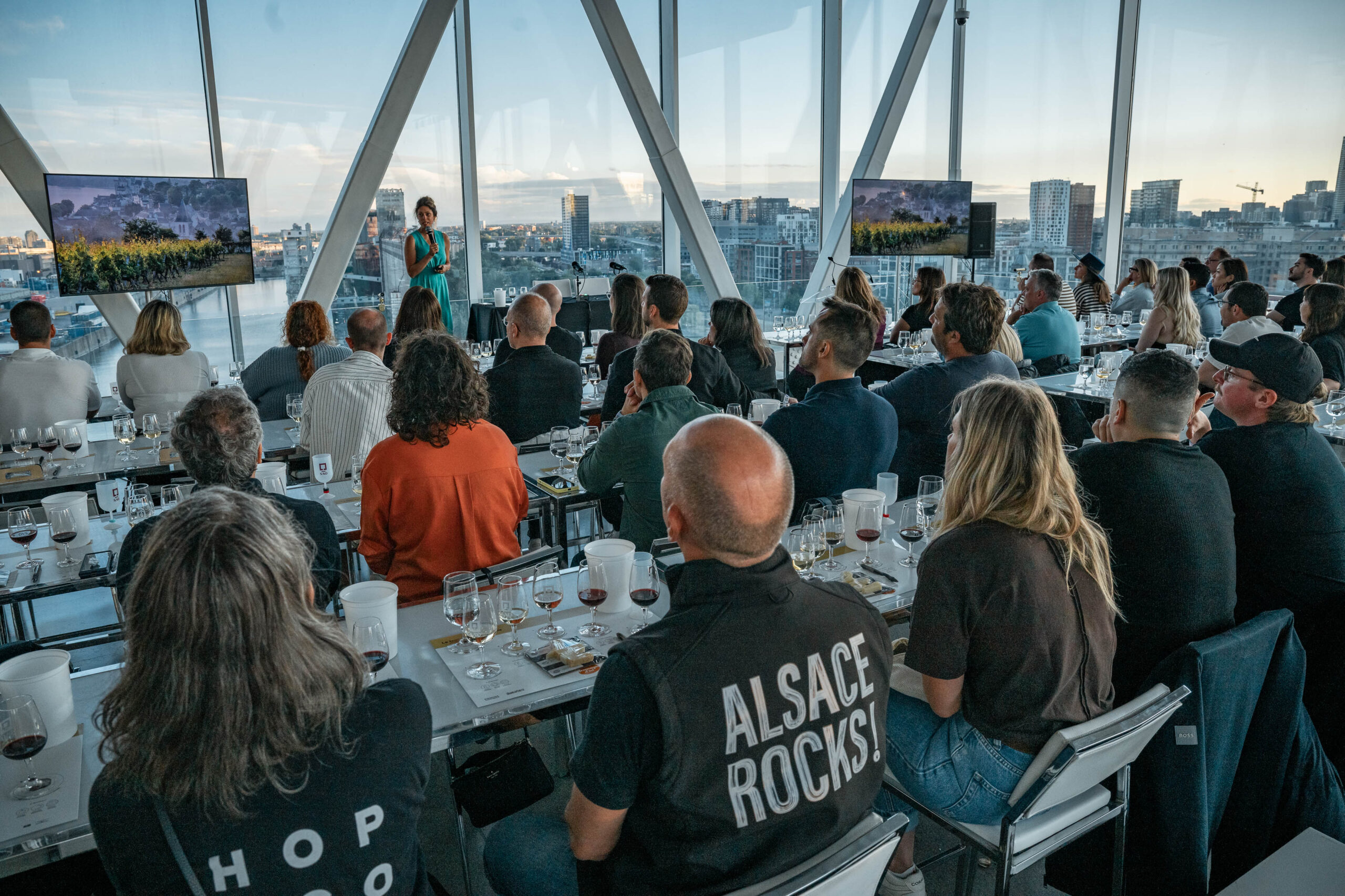 People sitting at a wine tasting event animated by a women, in front of city skyline