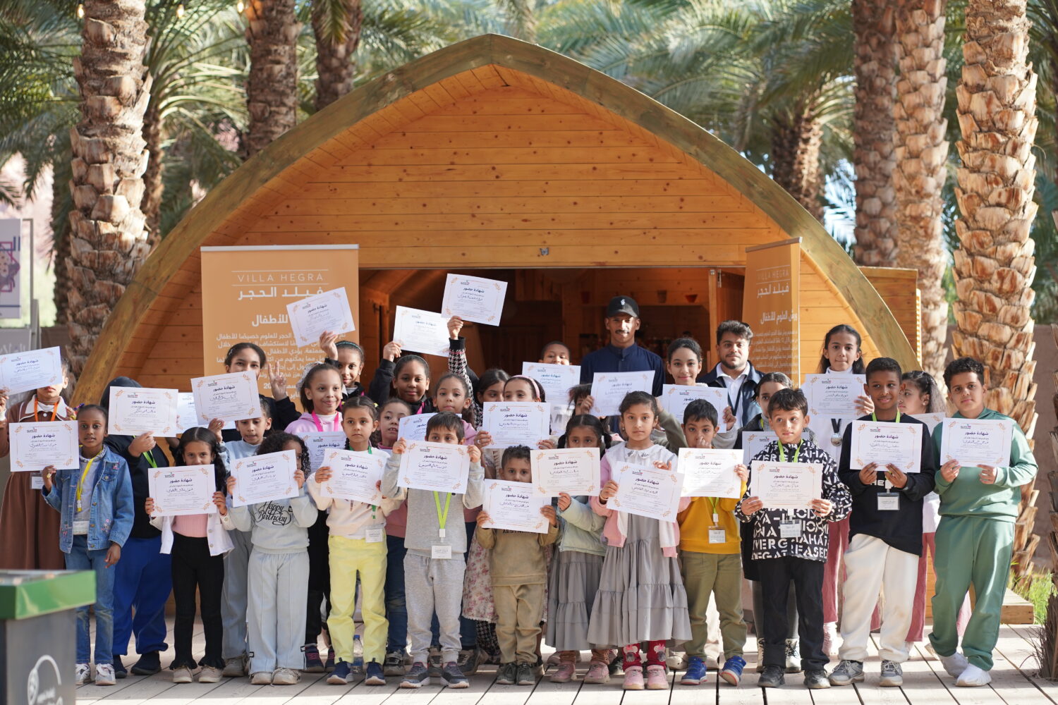 class of children all holding a certificate proudly in front of building