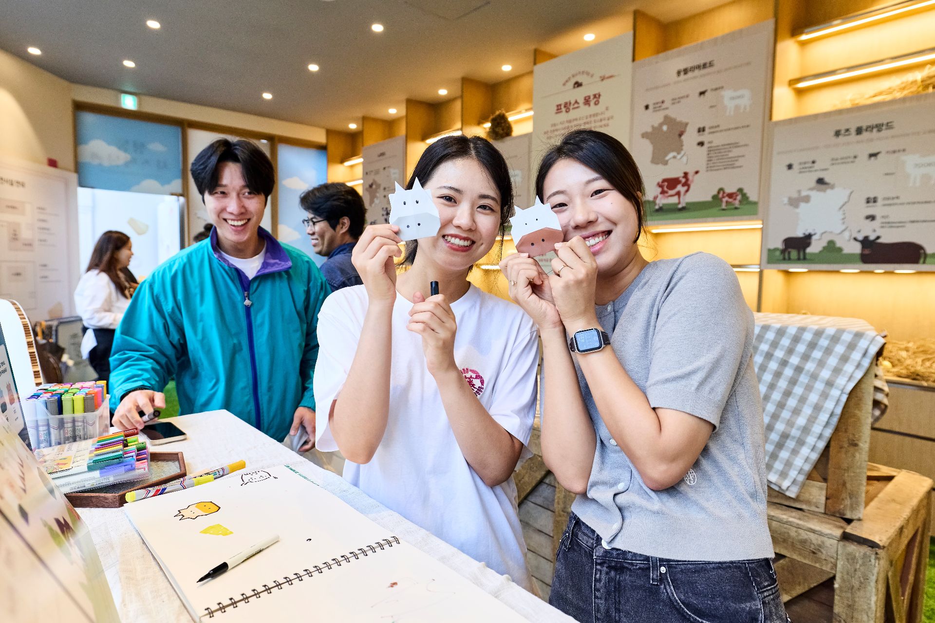Two women showing their papermade cows to the camera at an cheese event