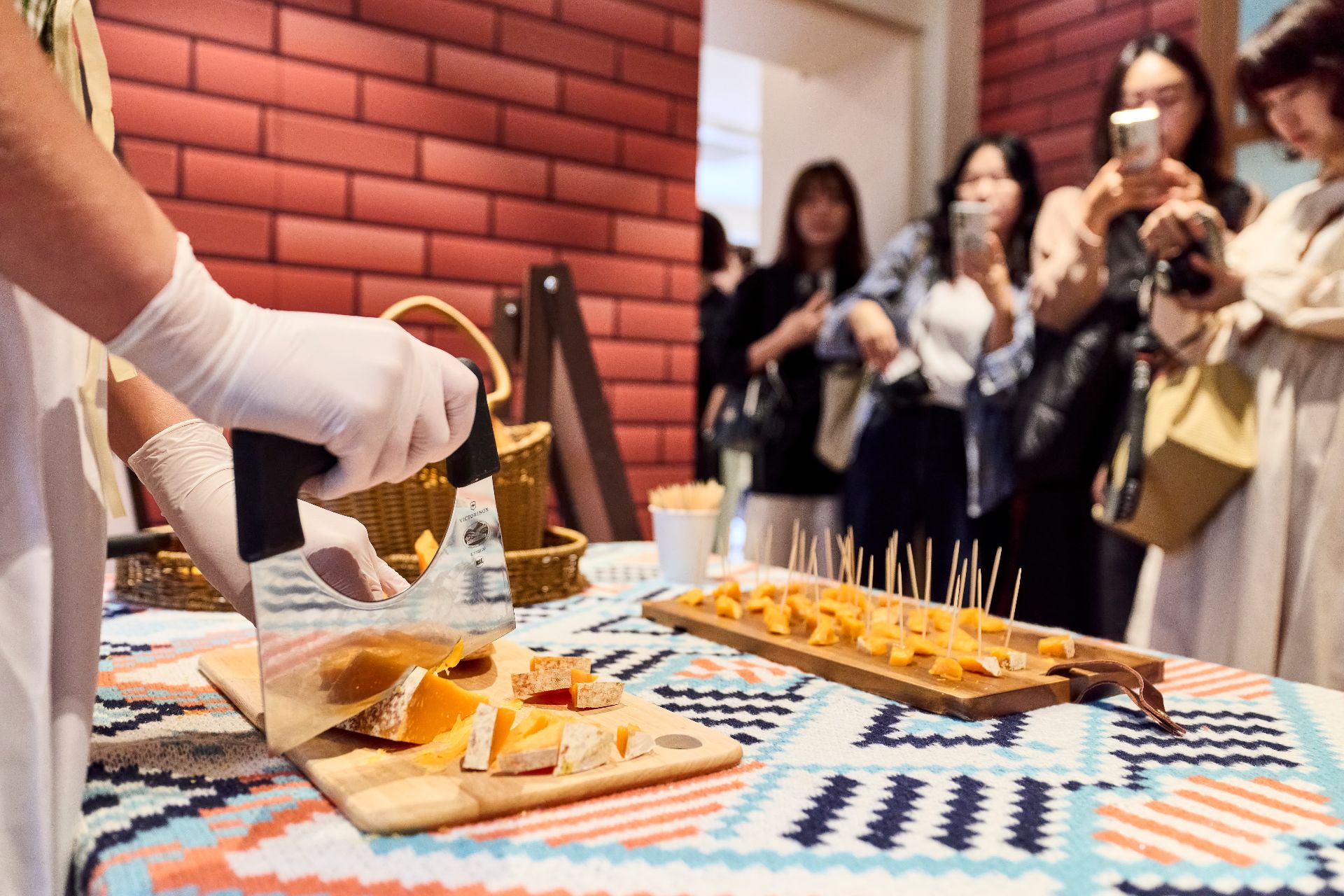 Cheese being cut for tasting in front of small crowd